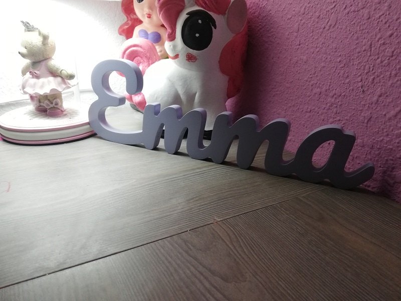 Nombresito Emma en morado sobre repisa